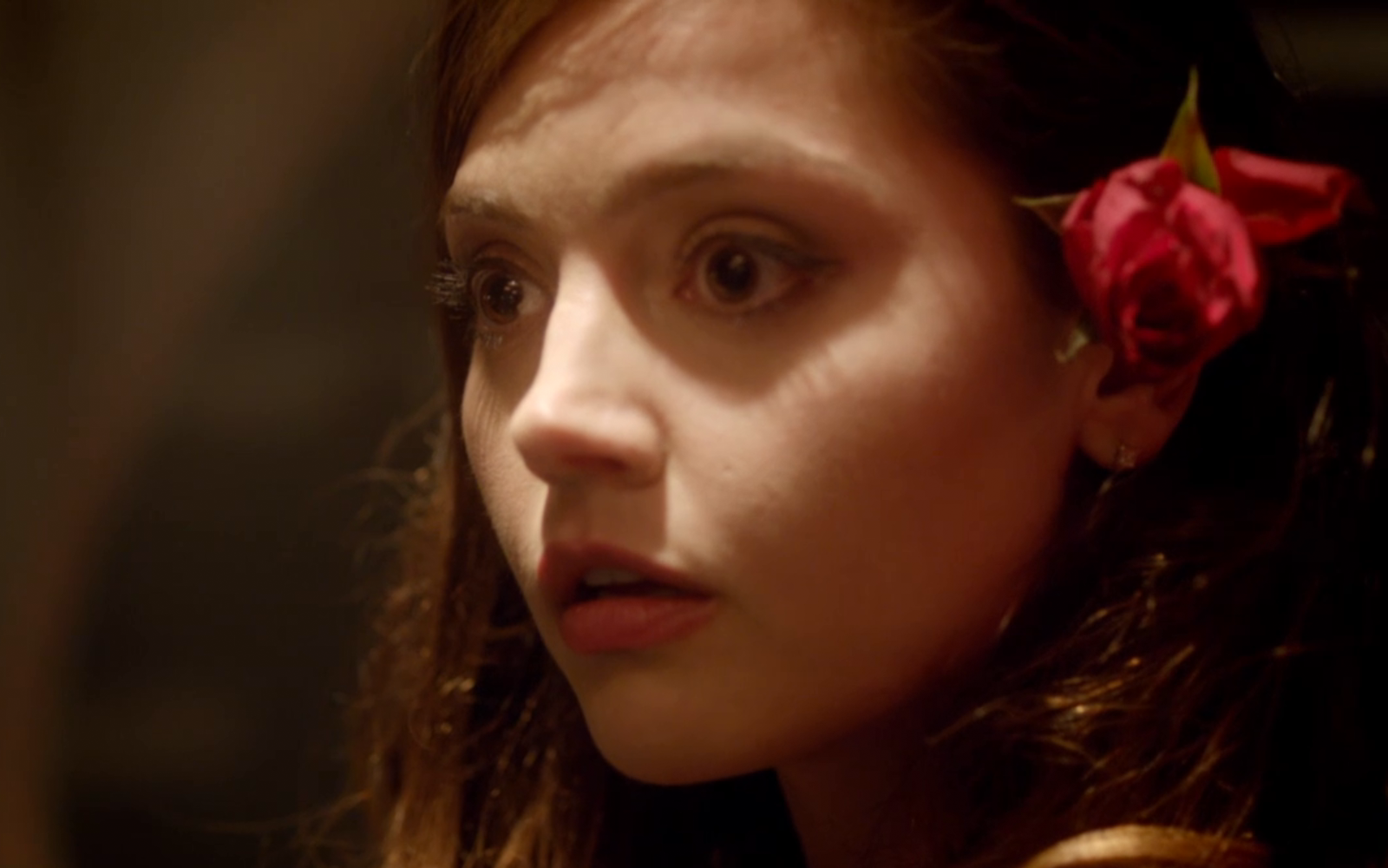Jenna Coleman as Clara Oswald from Doctor Who (2005) in a close-up shot with a red rose tucked behind her ear, featured in an HD PC desktop wallpaper.