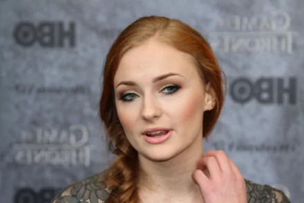 A close-up portrait of Sophie Turner, showcasing her distinct features and elegant styling, set against a backdrop promoting HBO's Game of Thrones. 4K Ultra HD desktop wallpaper.