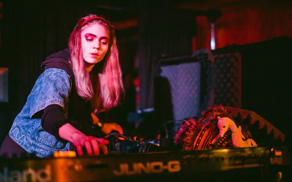 HD PC desktop wallpaper featuring Grimes performing music with electronic equipment in a dimly lit setting.