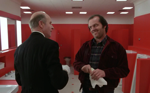 HD PC desktop wallpaper: movie scene in a stark red restroom where a grinning man in a red jacket faces another man, evoking the film The Shining.