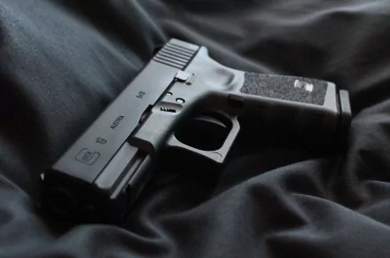 HD desktop wallpaper featuring a close-up of a man-made Glock 19 handgun resting on dark fabric.