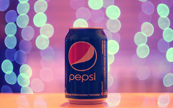 A high-definition desktop wallpaper displaying a Pepsi can set against a colorful, bokeh background with circular light patterns.