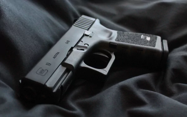 HD desktop wallpaper featuring a close-up of a man-made Glock 19 handgun resting on dark fabric.