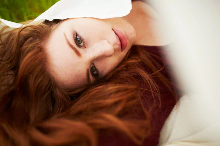 Close-up of a red-haired woman’s face in soft light, hair fanned on a pillow; 5K Ultra HD PC desktop wallpaper and background.