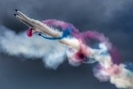 2K Quad HD PC Desktop Wallpaper and Background of military jets at an air show carving red, white and blue smoke trails across a brooding sky.