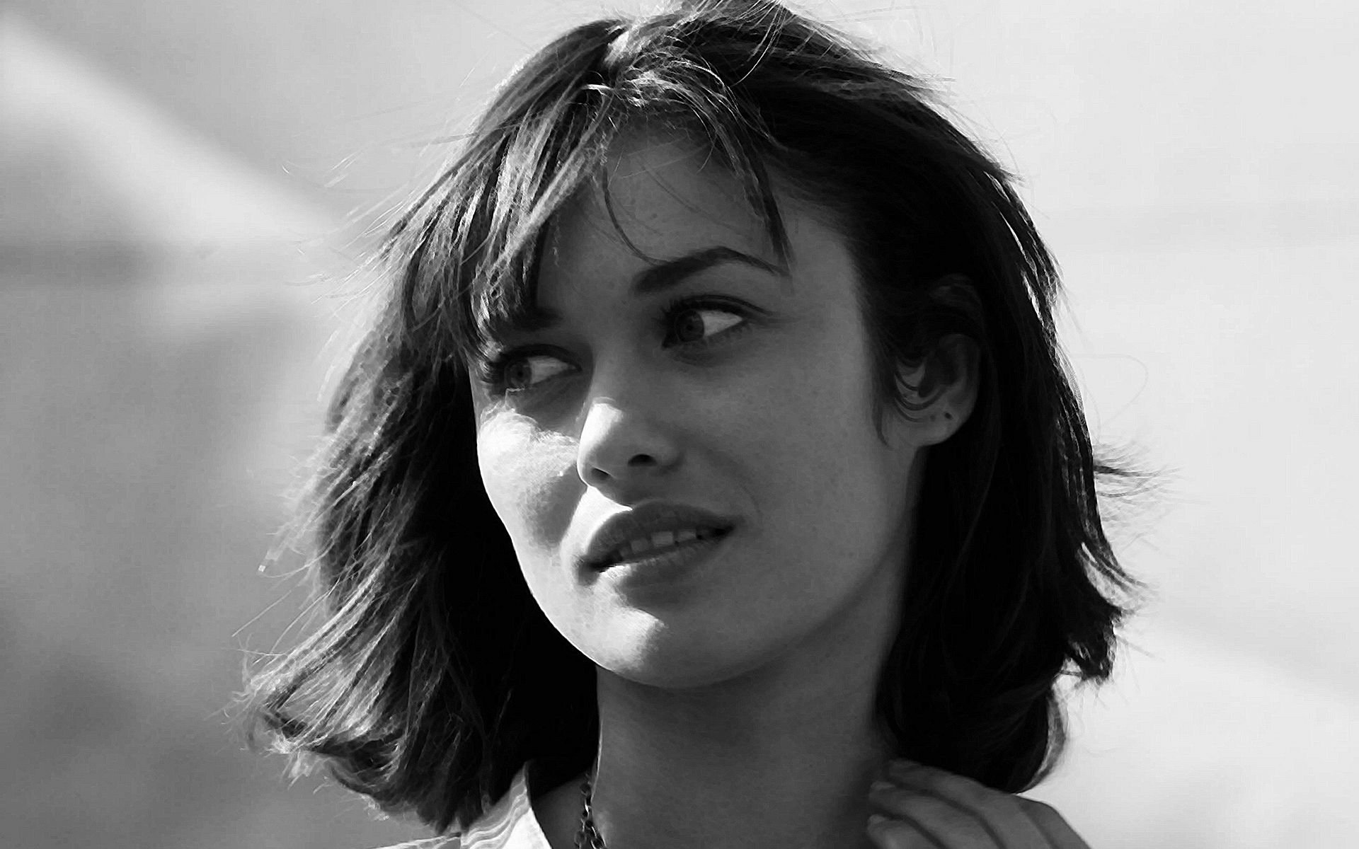 Black and white HD desktop wallpaper featuring celebrity Olga Kurylenko with a thoughtful expression.