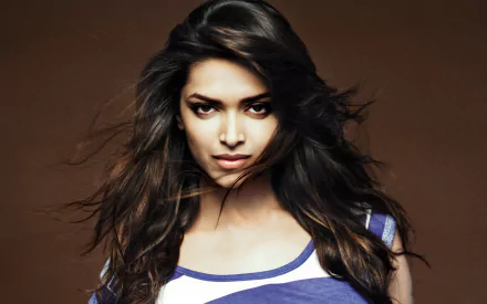 HD desktop wallpaper featuring Deepika Padukone, showcasing her striking expression and flowing hair against a warm brown background.