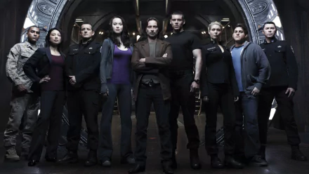 HD PC desktop wallpaper of characters from the TV show Stargate Universe standing united before a Stargate inside a dim, industrial ship interior.