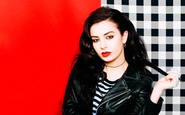 HD PC desktop wallpaper featuring Charli XCX with dark hair and red lipstick against a bold red and black-and-white checkered background, blending music and edgy style.