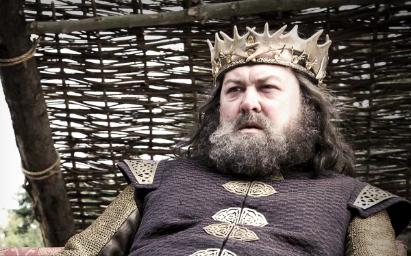 HD PC desktop wallpaper: Robert Baratheon from the Game of Thrones TV show — stern, bearded king in a crown and ornate robes seated before a woven backdrop