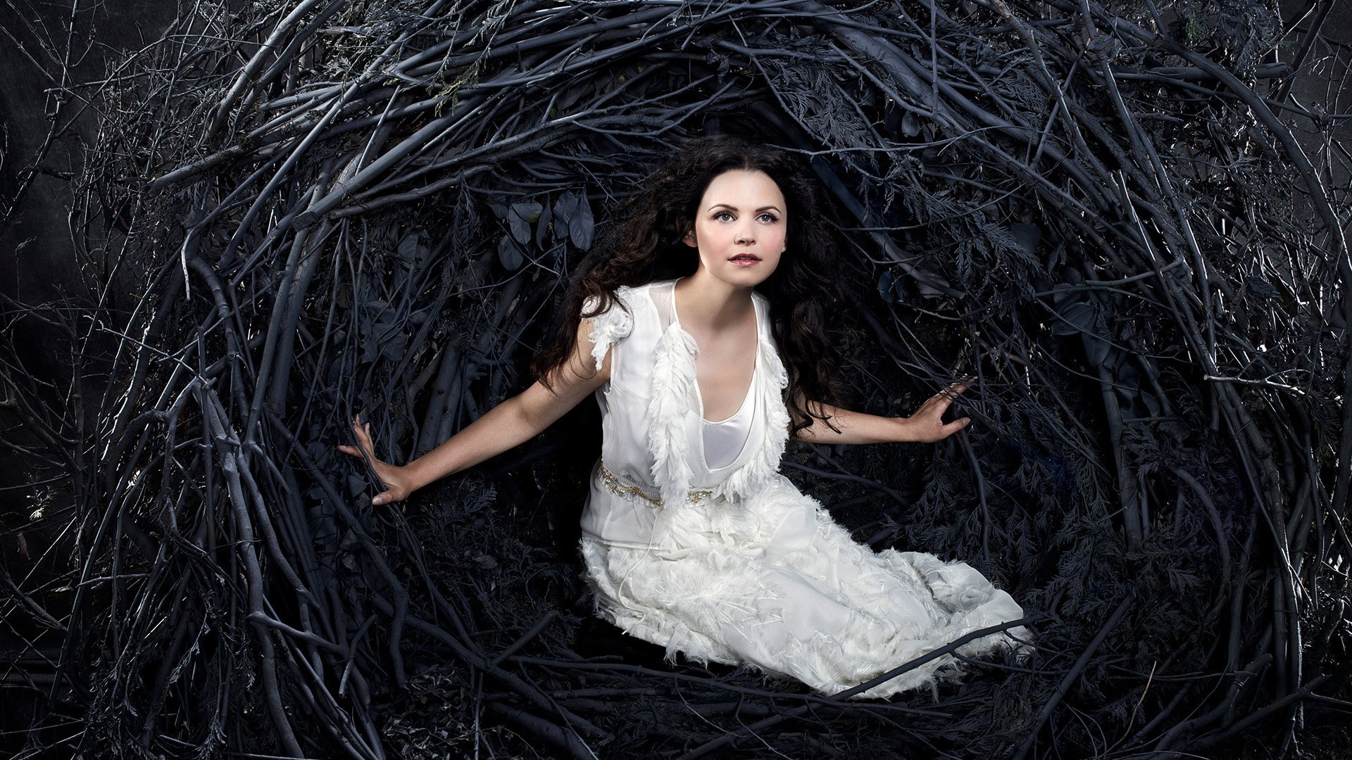 Snow White from the TV show Once Upon A Time sits in a dark, twisted nest of branches, featured in an HD PC desktop wallpaper background.