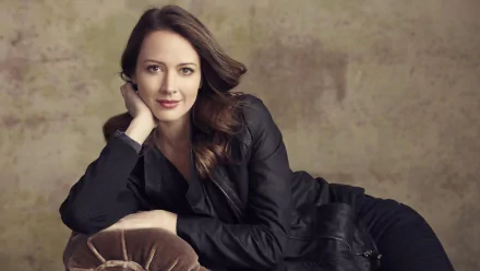 Amy Acker poses gracefully in a black outfit, showcasing her elegance against a muted backdrop, inspired by her role in the TV show Person of Interest. HD desktop wallpaper.