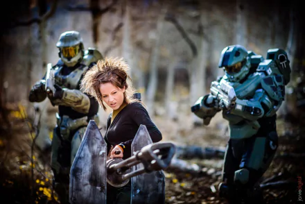 HD PC desktop wallpaper featuring Lindsey Stirling with a violin amidst two futuristic armored figures in a wooded setting, blending music and sci-fi elements.