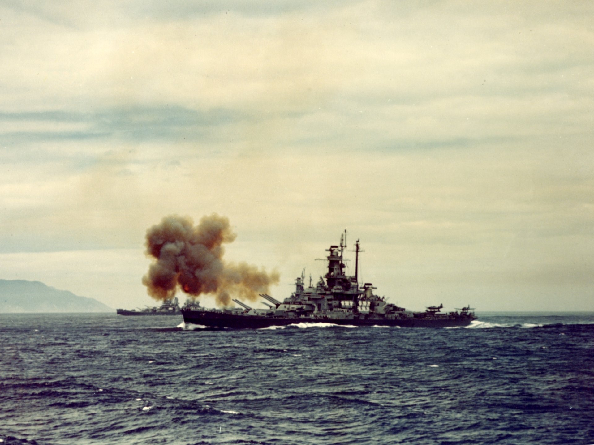 USS Indiana (BB-58) battleship of the United States Navy firing a broadside on the open sea, 2K Quad HD PC desktop wallpaper.