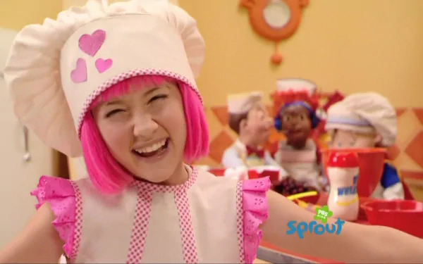 HD desktop wallpaper from the TV show LazyTown featuring Stephanie in a pink and white chef outfit smiling brightly in a kitchen setting.