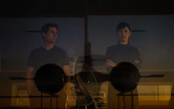 A dramatic image from the movie Oblivion, featuring Tom Cruise and Olga Kurylenko, set against a backdrop with silhouettes of aircraft, highlighting a tense moment in a sci-fi landscape.