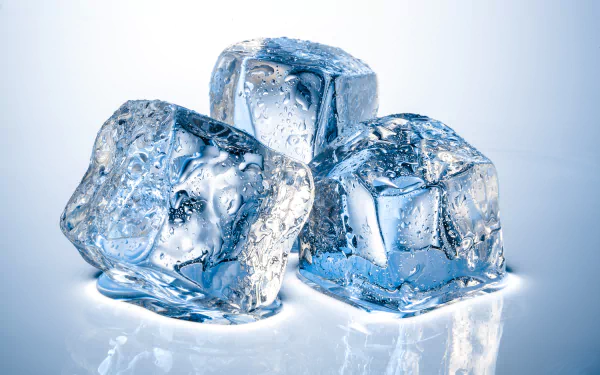Close-up photography of three glistening ice cubes, showcasing intricate textures and reflections, set against a softly lit background. This image serves as a striking HD desktop wallpaper.