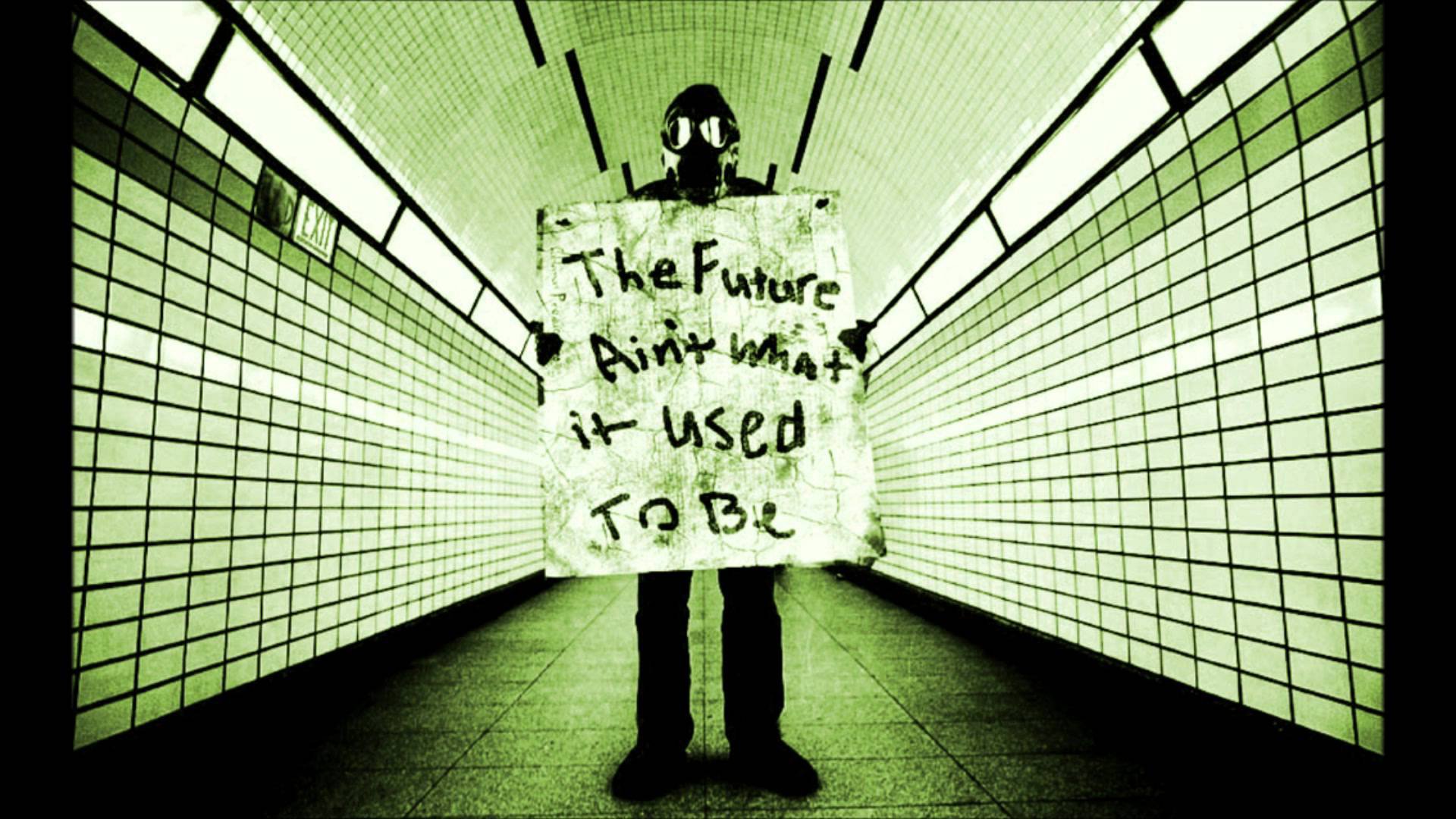 A Sci-Fi, post-apocalyptic HD wallpaper depicts a person in a gas mask holding a sign that reads, The Future Ain't What It Used To Be, standing in an eerie, tiled hallway.