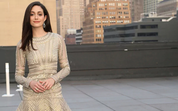 HD desktop wallpaper featuring celebrity Emmy Rossum in an elegant, shimmering gown standing on a rooftop with a cityscape background.