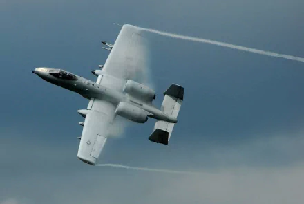 A Fairchild Republic A-10 Thunderbolt II maneuvers through a cloudy sky, leaving vapor trails behind. This dynamic image serves as a striking military-themed HD desktop wallpaper.