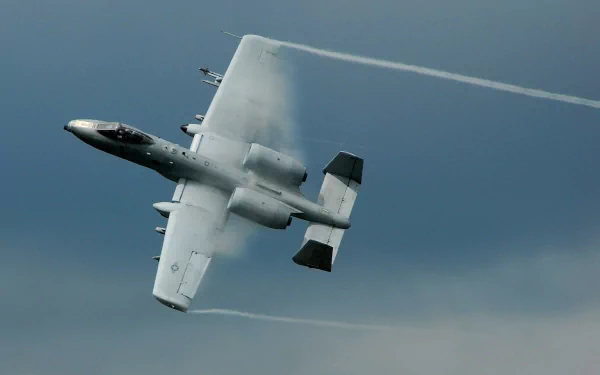 A Fairchild Republic A-10 Thunderbolt II maneuvers through a cloudy sky, leaving vapor trails behind. This dynamic image serves as a striking military-themed HD desktop wallpaper.