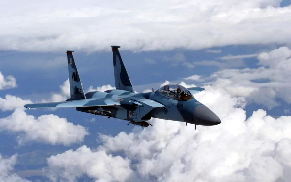 HD desktop wallpaper featuring a McDonnell Douglas F-15 Eagle military jet flying above white clouds against a blue sky.
