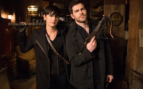 A striking HD wallpaper featuring characters from the TV show Grimm, showcasing a duo in dark attire, ready for action against a mysterious backdrop.