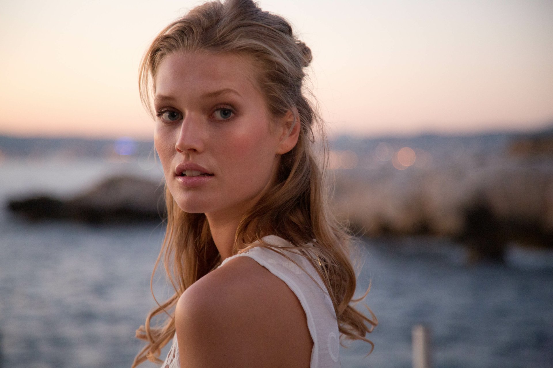 HD PC desktop wallpaper featuring a close-up portrait of woman Toni Garrn with a serene ocean backdrop at sunset.