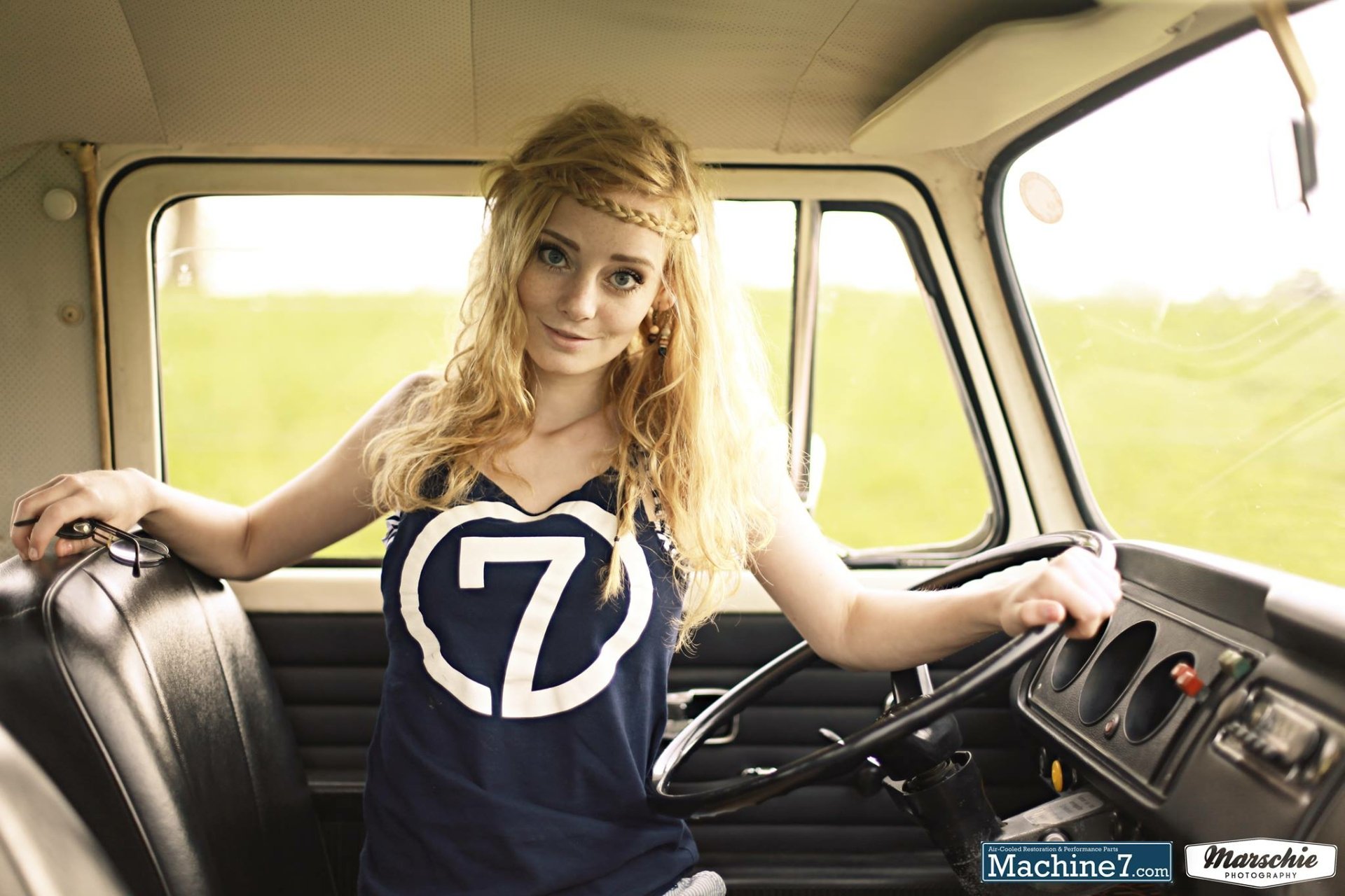 A high-definition desktop wallpaper featuring a woman, Freyja Vanden Broucke, inside a vintage vehicle with a relaxed and confident pose, creating a serene atmosphere.