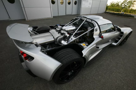 A high-definition image of a silver Hennessey Venom GT supercar, showcasing its sleek design and impressive rear engine components, set against a minimalistic backdrop.
