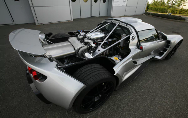 A high-definition image of a silver Hennessey Venom GT supercar, showcasing its sleek design and impressive rear engine components, set against a minimalistic backdrop.