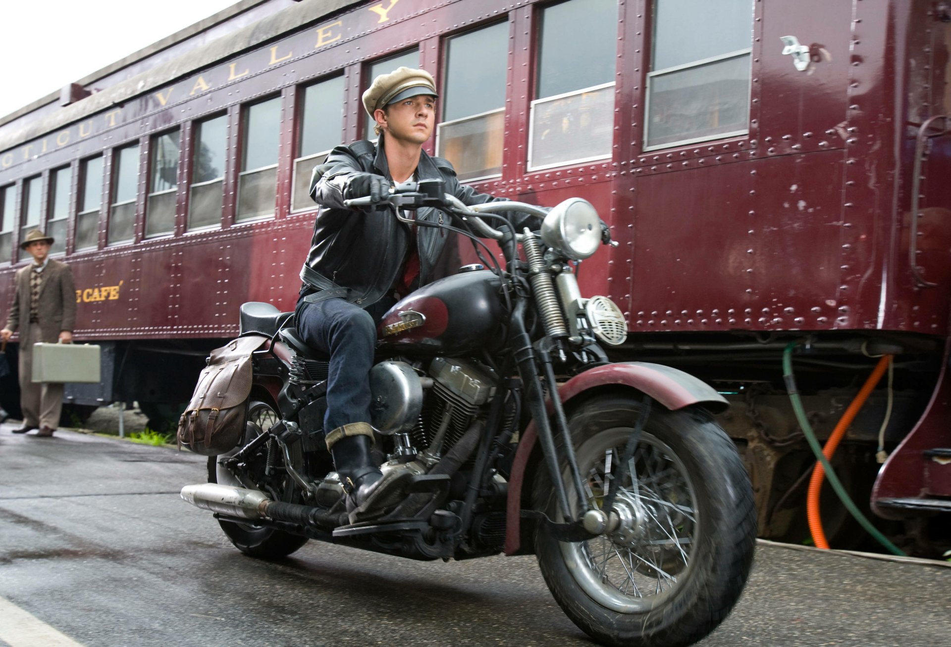 Shia LaBeouf riding a motorcycle beside a vintage train, from the movie Indiana Jones and the Kingdom of the Crystal Skull, captured as an HD PC desktop wallpaper.