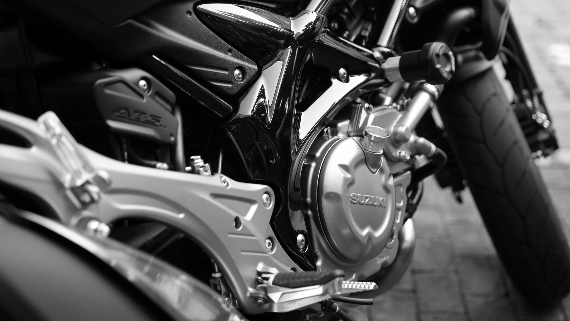 Close-up 4K Ultra HD wallpaper of a Suzuki motorcycle engine and rear wheel in black-and-white, showing detailed bike components and frame.
