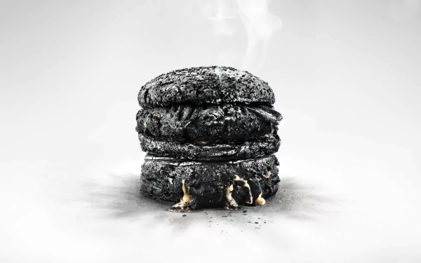 HD desktop wallpaper featuring a dramatically charred burger with smoke against a gray background.