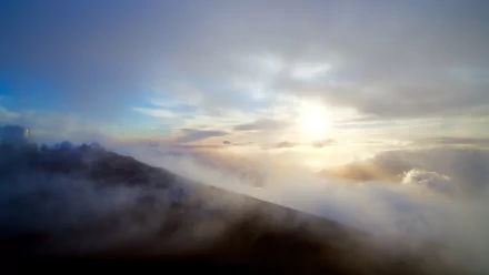 A stunning 4K Ultra HD landscape showing sunbeams piercing through clouds and fog over a serene natural sky.