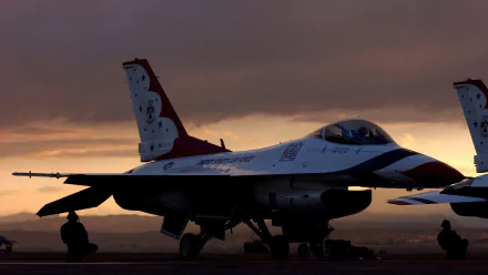 HD desktop wallpaper of a General Dynamics F-16 Fighting Falcon from the United States Air Force Thunderbirds, set against a dramatic sunset sky.