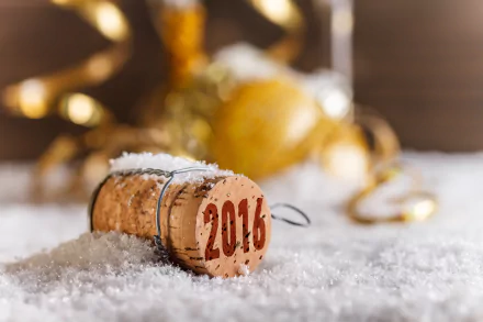 Holiday New Year 2016 4K Ultra HD PC desktop wallpaper: close-up of a champagne cork stamped 2016 in snow, with golden baubles and curled ribbon blurred behind.