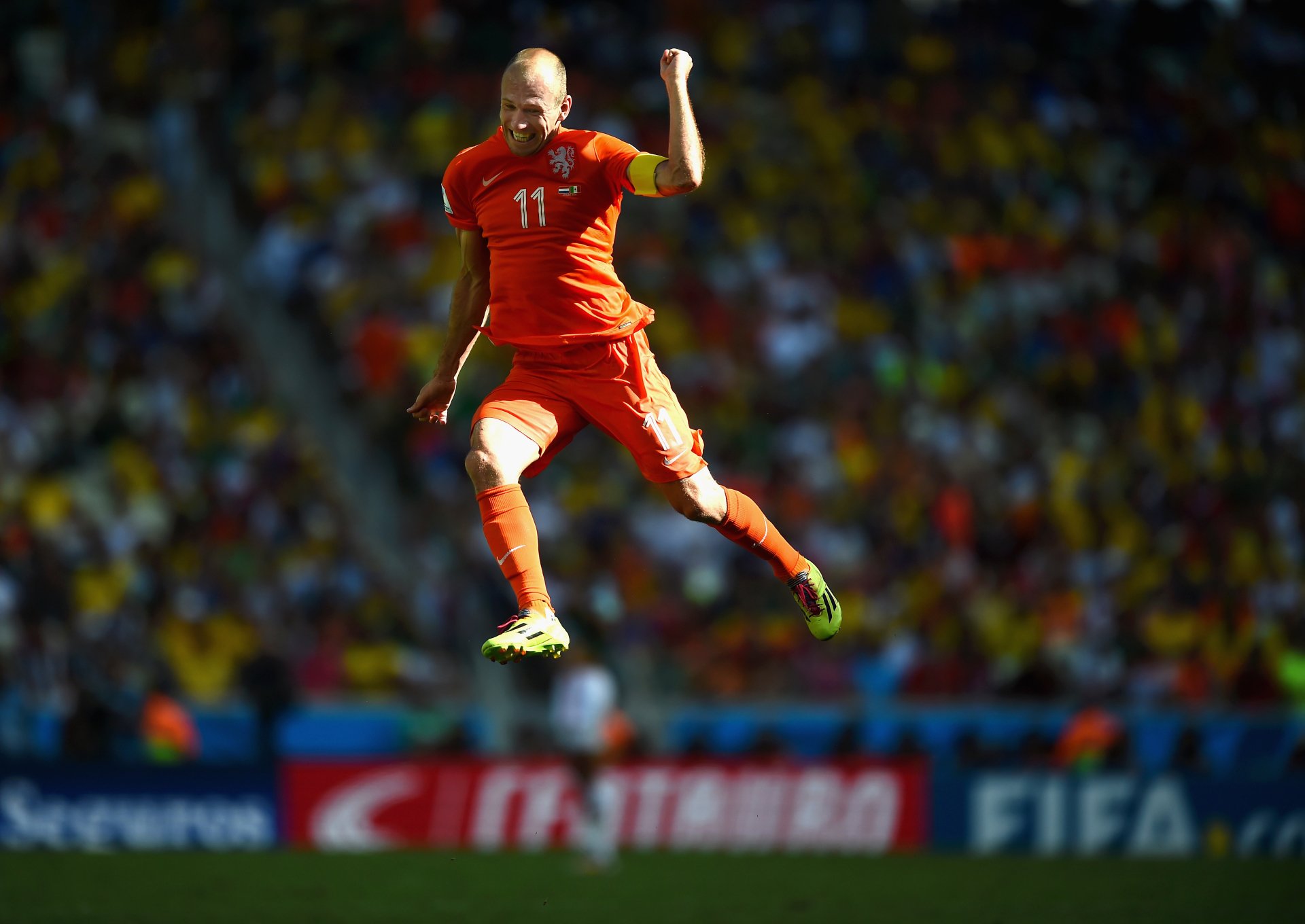 4K Ultra HD PC desktop wallpaper showing a soccer player in an orange uniform mid-air during a dynamic sports moment on a crowded stadium field.