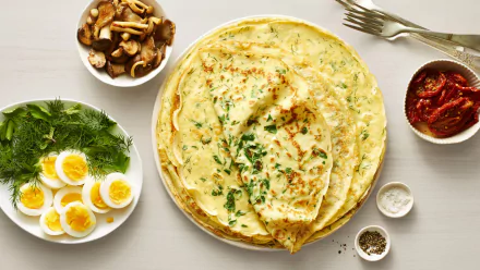 HD PC desktop wallpaper of food: savory crêpes on a plate garnished with herbs, surrounded by bowls of boiled eggs, mushrooms, sun-dried tomatoes and seasonings.