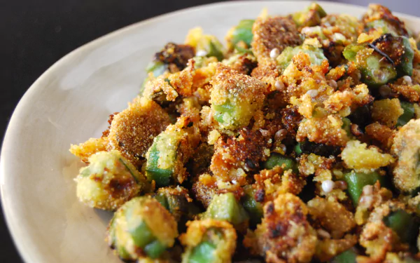 4K Ultra HD PC desktop wallpaper: close-up of sautéed okra food with golden crumbs and spices on a white plate, vibrant textures and warm, rustic tones.