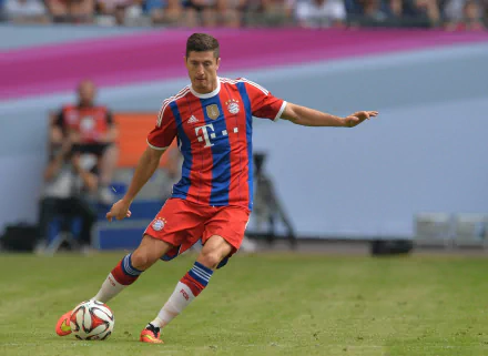 HD desktop wallpaper featuring Polish soccer player Robert Lewandowski in a red and blue sports uniform, captured mid-action on the field.