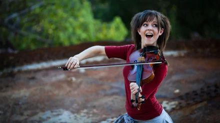 HD desktop wallpaper featuring Lindsey Stirling joyfully playing the violin outdoors, capturing her dynamic energy and musical passion.