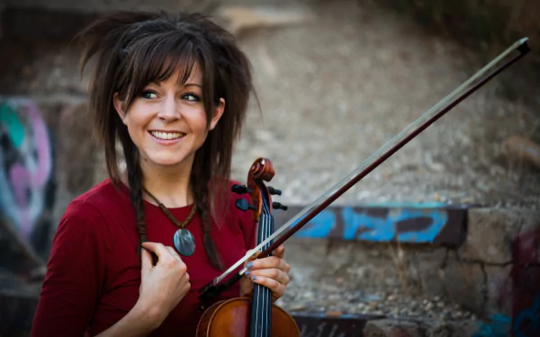 Lindsey Stirling smiling with her violin in hand against an urban backdrop, captured in vibrant 4K Ultra HD for a music-themed PC desktop wallpaper.
