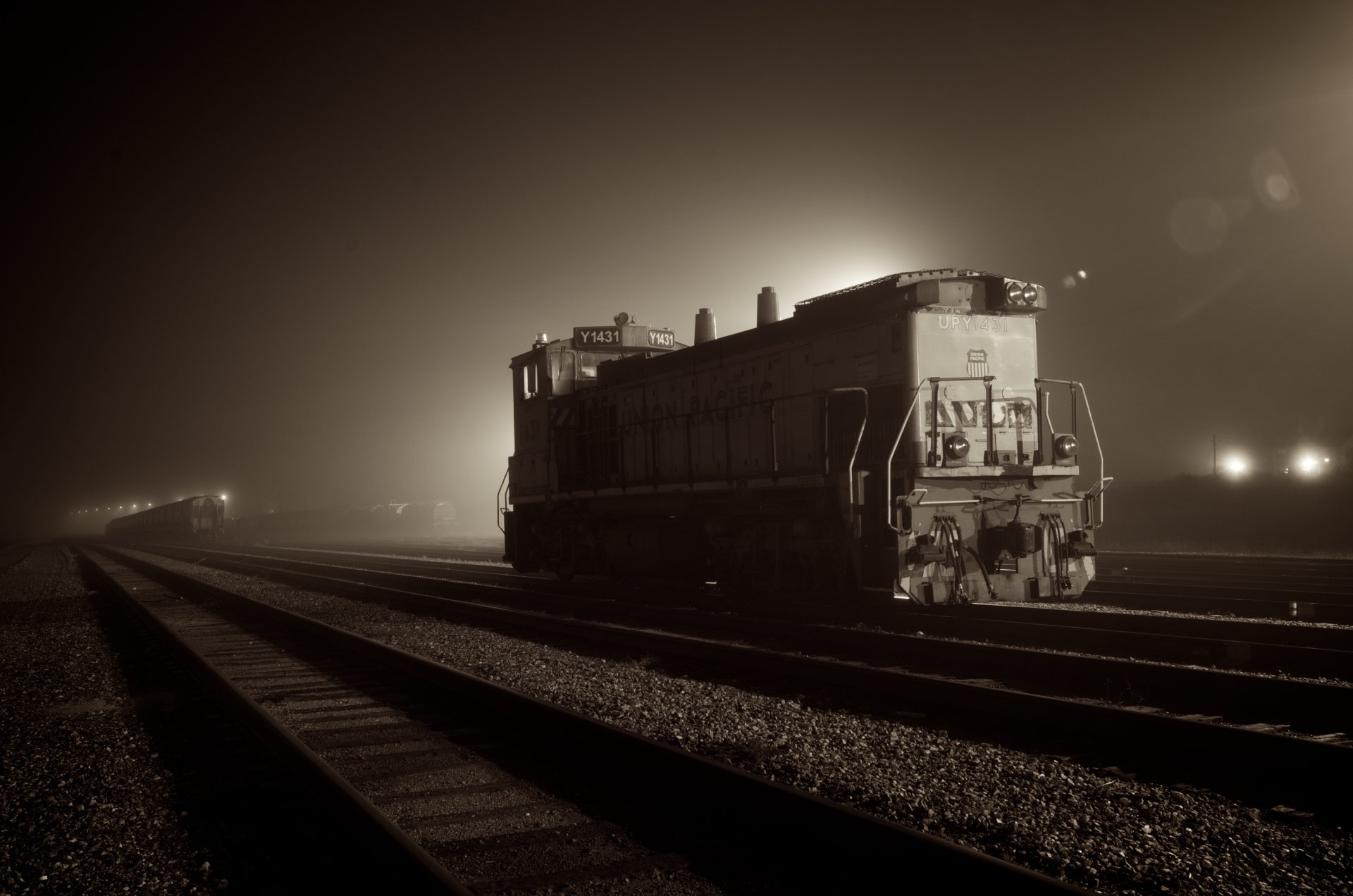 4K Ultra HD PC desktop wallpaper showing a vehicle — a diesel train — idling on foggy night tracks in sepia tones with distant lights.