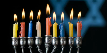 HD PC desktop wallpaper of a Hanukkah menorah with nine lit colorful candles against a dark blue background, capturing the holiday's festive spirit.