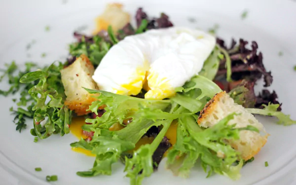 Close-up of a Salade Lyonnaise with fresh lettuce, a poached egg, and croutons, captured in 4K Ultra HD as a vibrant lunch meal wallpaper.
