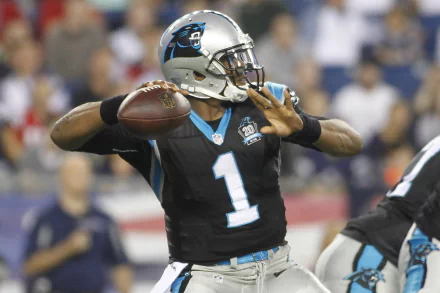 HD PC desktop wallpaper showing a Carolina Panthers player (#1) in black uniform throwing a football during a live sports game background.
