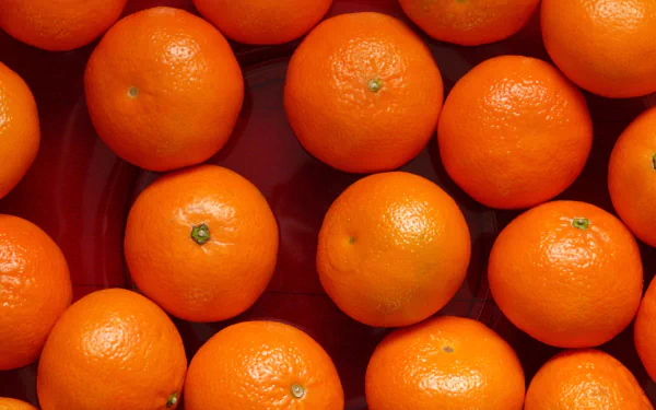 Close-up of glossy mandarin oranges filling the frame, a vibrant food photo presented as a 2K Quad HD PC desktop wallpaper/background.