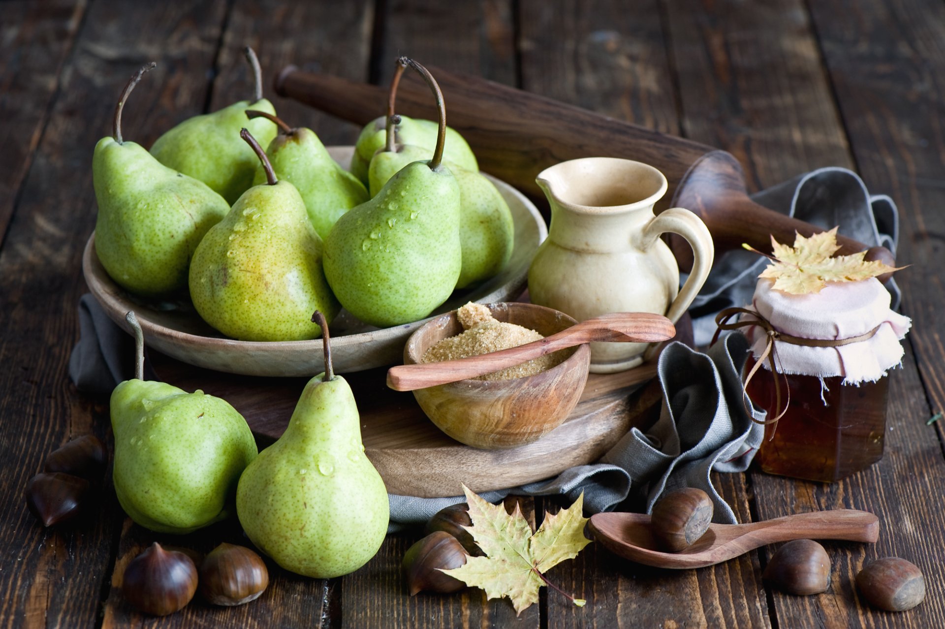HD still life desktop wallpaper featuring fresh green pears, honey jar, wooden utensils, and autumn leaves on a rustic wooden table, evoking the fall season.