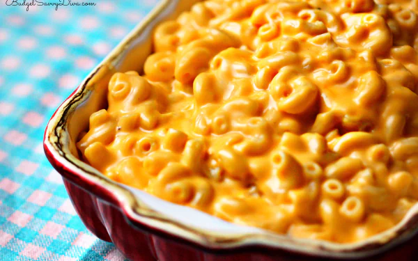 HD desktop wallpaper: close-up of creamy macaroni and cheese in a red baking dish on a blue-checkered cloth, golden pasta filling the frame.